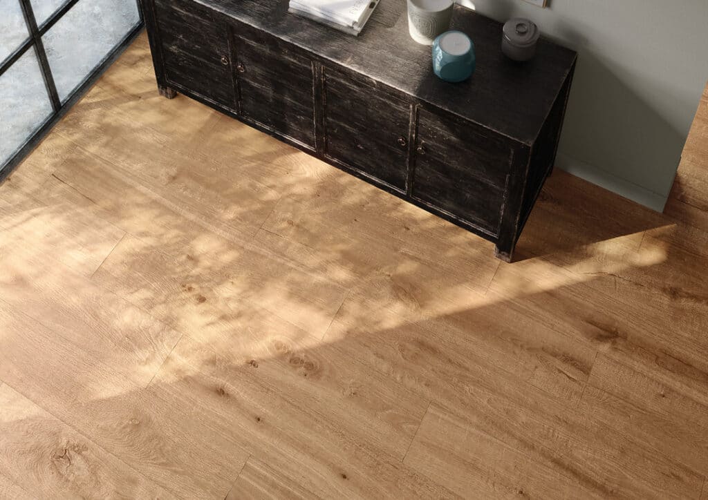 Holzoptikfliesen in gleichen Farbton verfugt mit einer alten Kommode