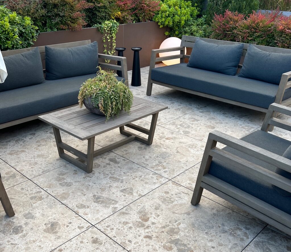 Terrasse mit Sitzmöbeln aus Holz, auf dem Boden die Terrassenfliese Norr.