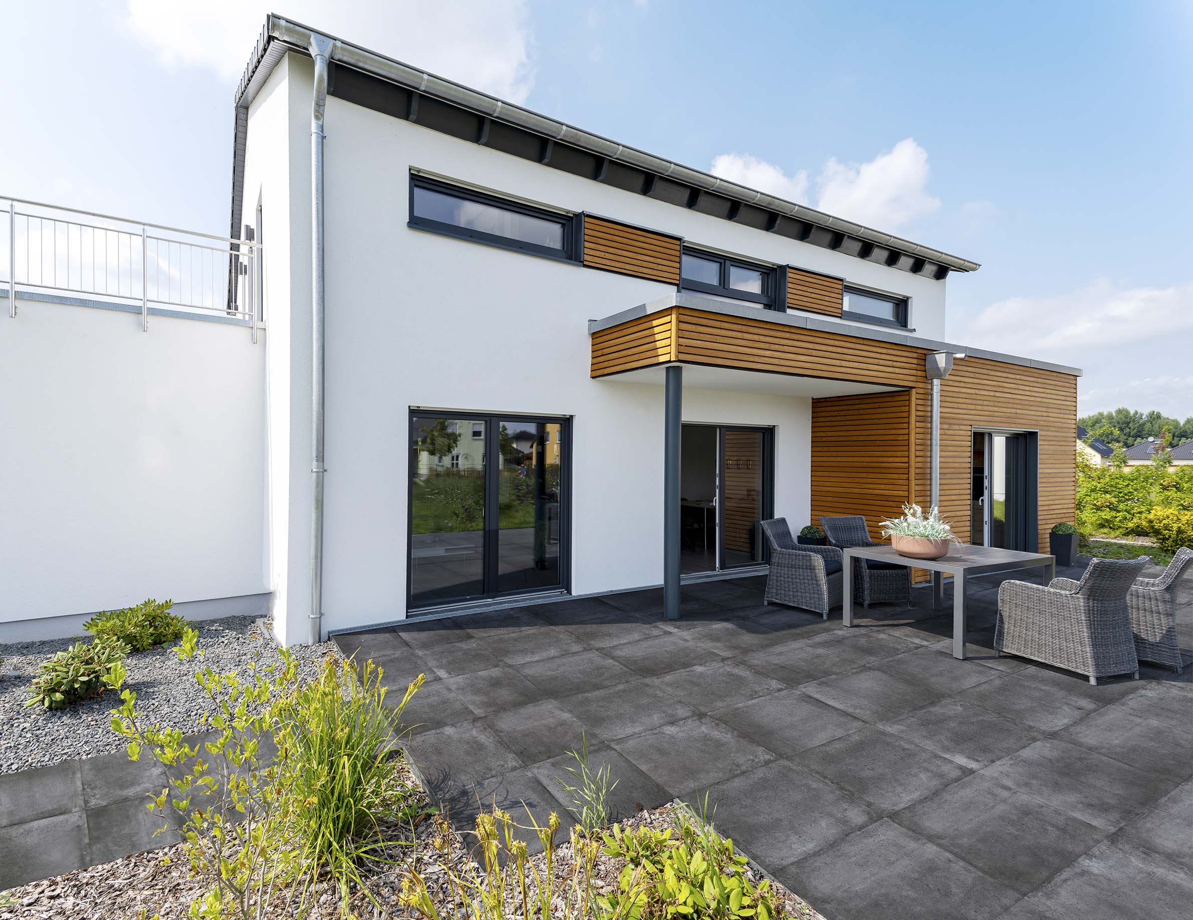Terrasse in Anthrazit gefliest. Dazu eine Holzüberdachung am Haus.