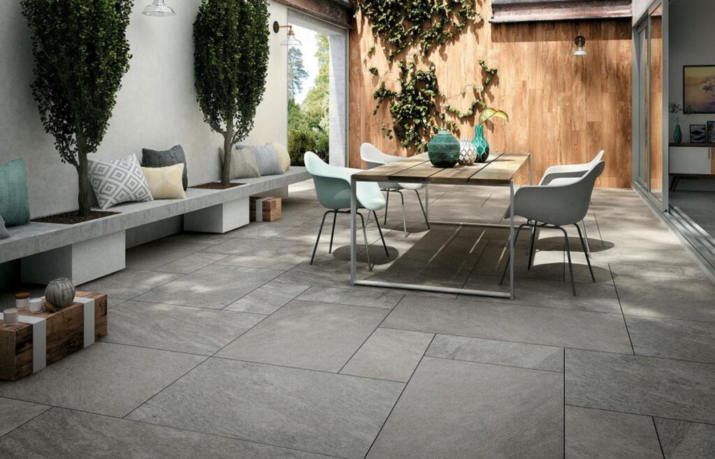 Terrasse mit gefliester Bank und Terrassenmöbel. Die Terrasse wurde mit einer grauen Quarzitoptikfliese gefliest. 