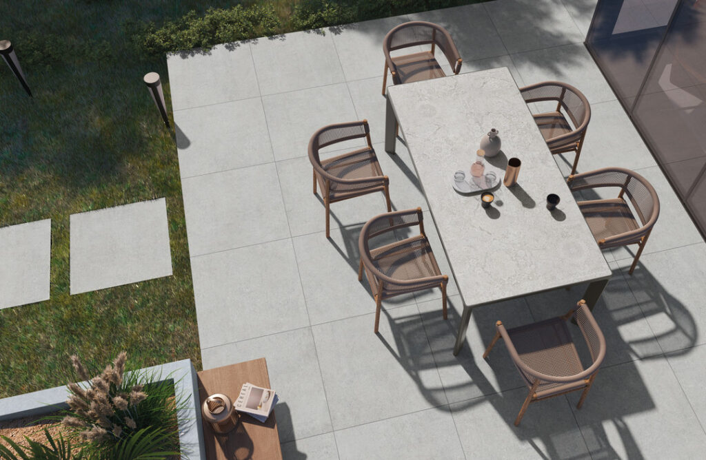 Terrasse von oben fotografiert mit Esstisch und 8 Stühlen, dazu eine Betonoptik auf den Boden