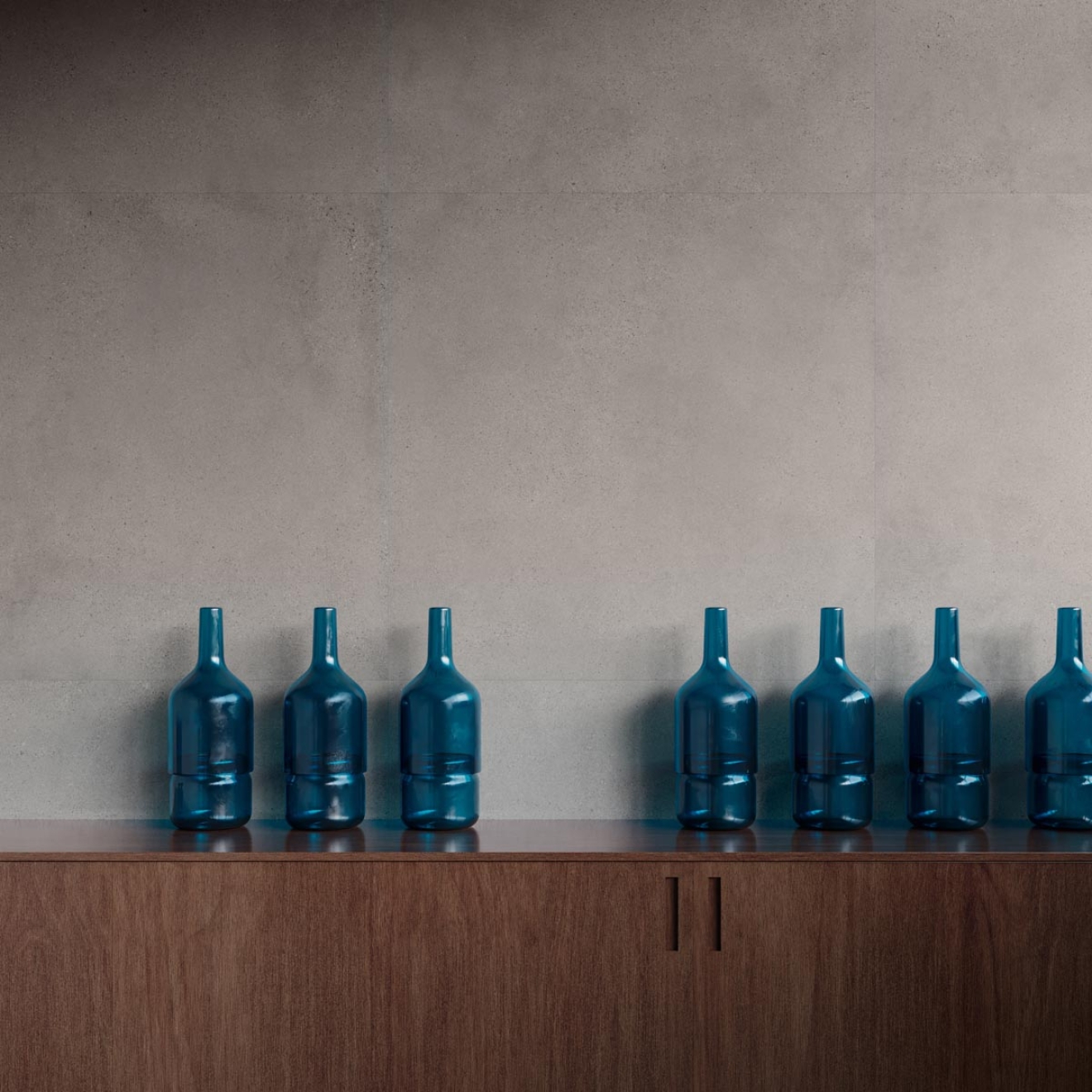 Fliese Sant Agostino Logico in der Farbe Grey verlegt hinter einer Kommode mit Glasflaschen