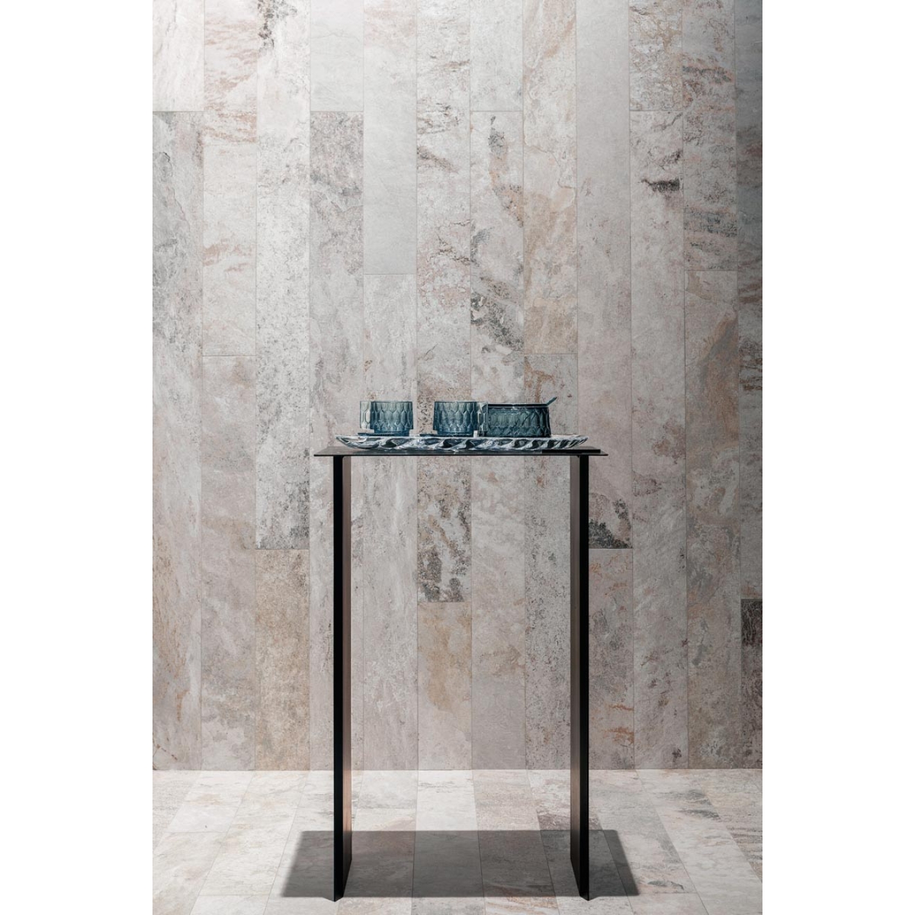 Fliese Sant Agostino Metastone in der Farbe Mud verlegt hinter einem Tisch mit Gläsern