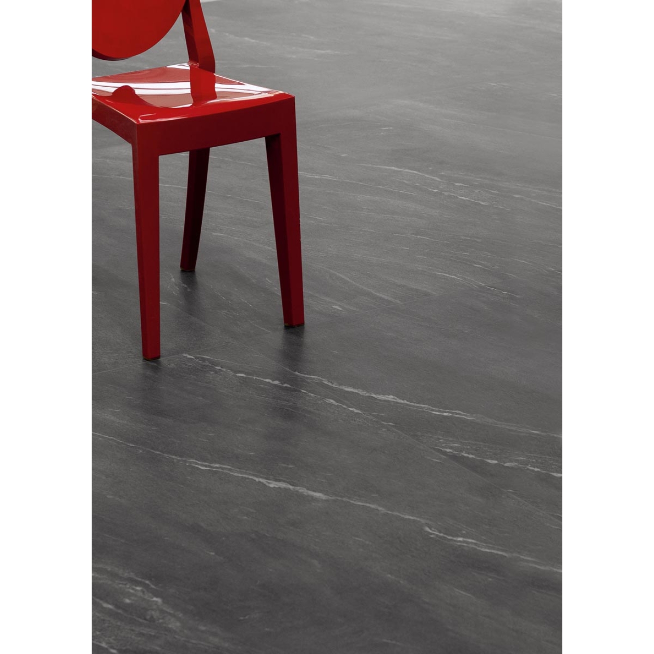 Fliese Sant Agostino Waystone in der Farbe Dark verlegt unter einem roten Stuhl