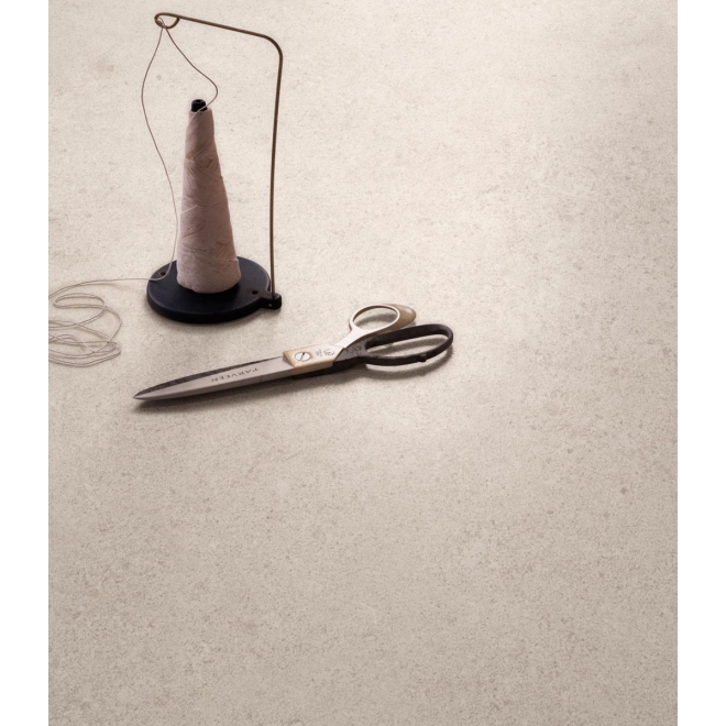 Fliese Sant Agostino Highstone in der Farbe Greige verlegt unter Faden und einer Schere