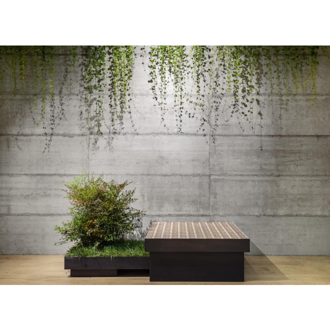 Fliese Sant Agostino Form in der Farbe Cement verlegt hinter einer Pflanze und einer Sitzmöglichkeit