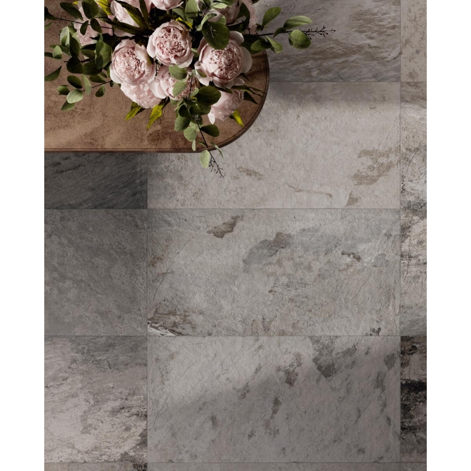 Fliese Sant Agostino Metastone in der Farbe Fog verlegt unter einem Tisch mit einem Blumenstrauß