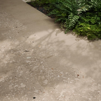 Fliese Sant Agostino Logico in der Farbe Cosmo Sand verlegt vor einem Busch