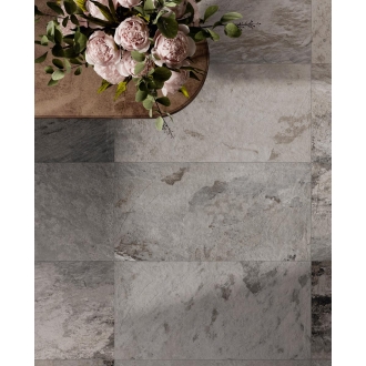 Fliese Sant Agostino Metastone in der Farbe Fog verlegt unter einem Tisch mit einem Blumenstrauß